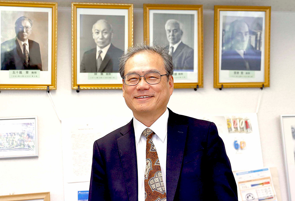 Professor MORITA Koichi smiles indoors.
