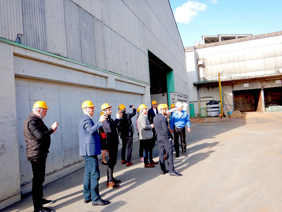 People in helmets standing and listening to an explanation at the facility. DAIEI KANKYO CO., LTD.