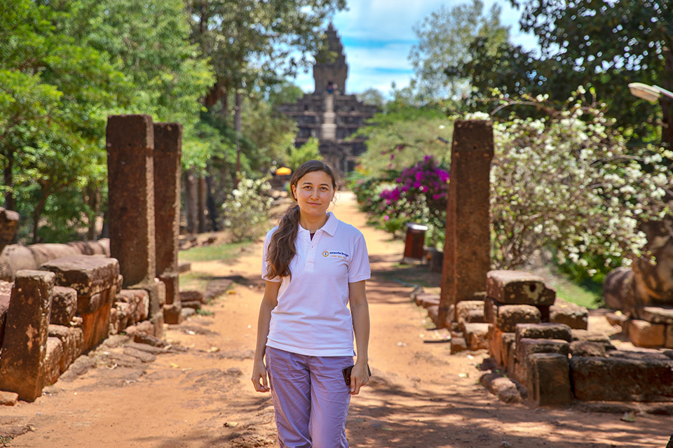 Zilya Yagafarova, a project manager at SORAMITSU, standing in beautiful historical site with ruins and trees in background.