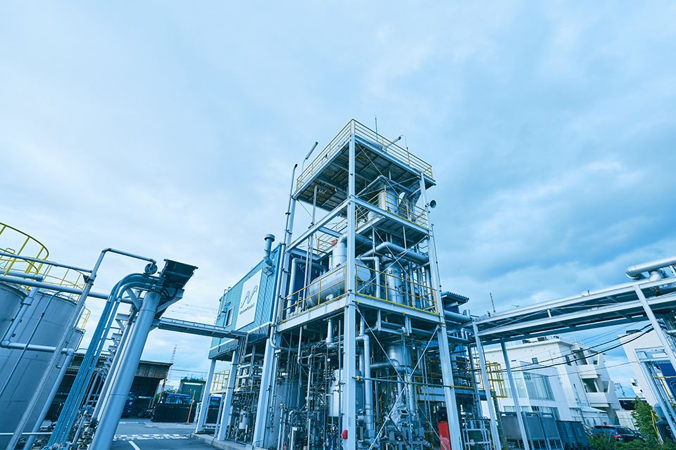 A complex industrial facility with multiple levels of metal platforms, pipes, and tanks under a cloudy sky.