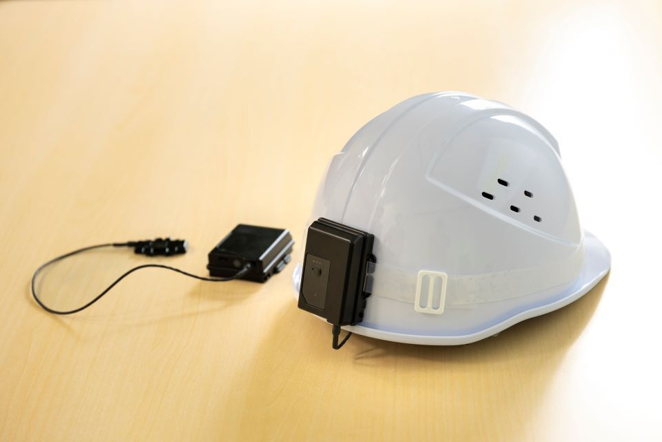 A white helmet with a sensor device attached to the back.