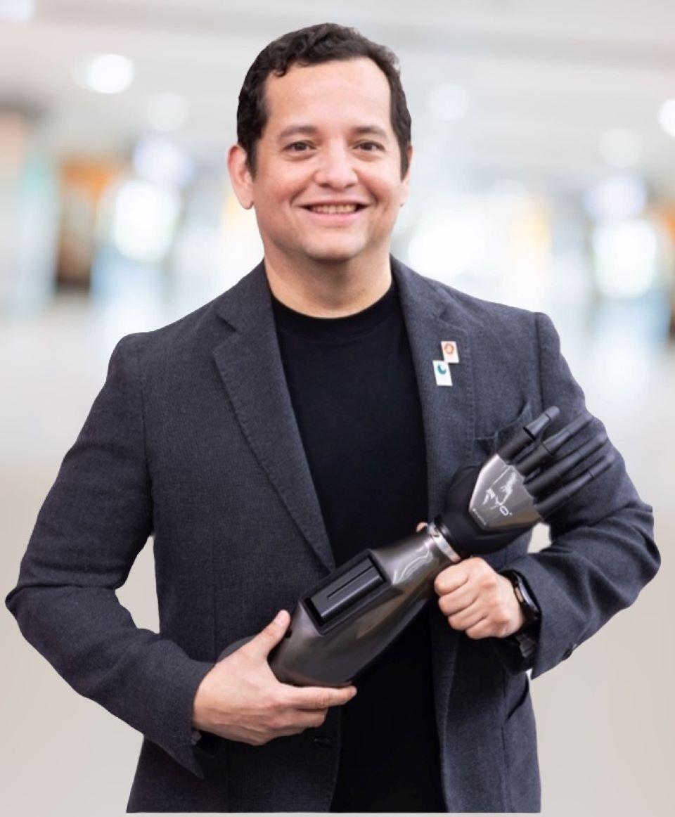A man in a suit holds a bionic robot hand.