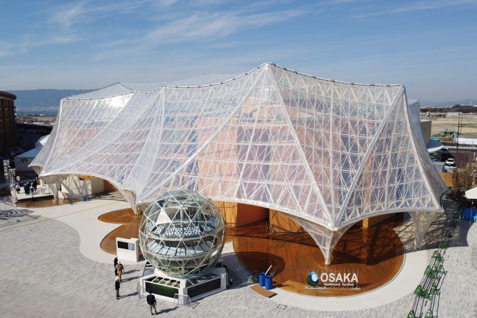 Osaka Healthcare Pavilion with a transparent, tent-like architectural structure and a geodesic dome in front.
